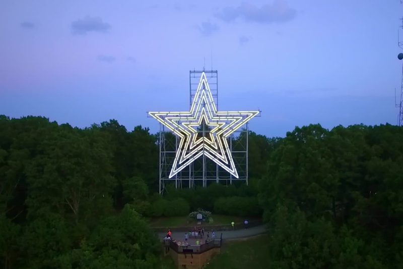 A birds-eye view of a giant lit up on top of Mill Mountain in Roanoke at dusk