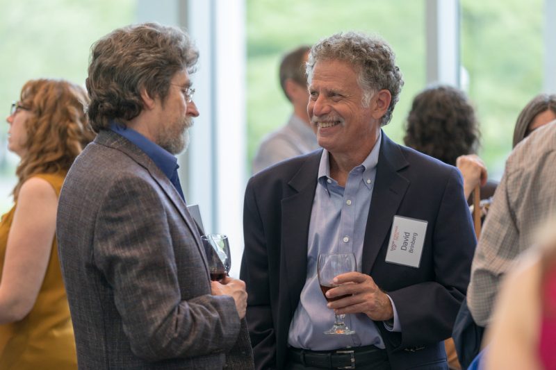Shot of David Brinberg at a reception smiling and talking with another individual