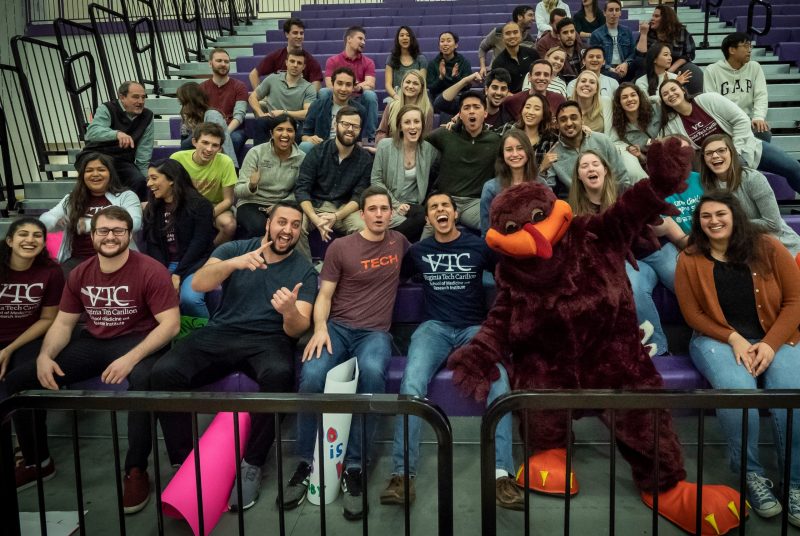 Students cheering in bleachers along with the Hokie Bird 