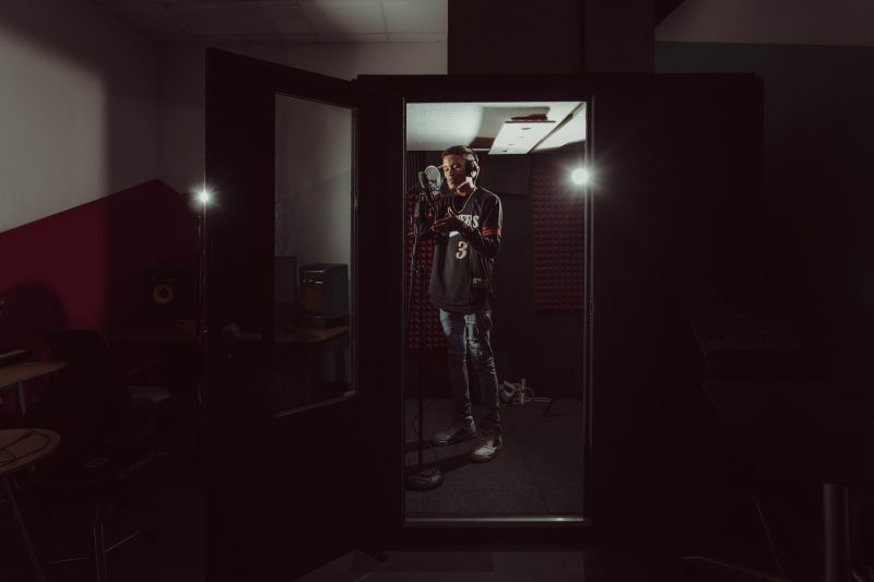 DeRay Manning stands in a recording booth in the Media Design Studio in Newman Library 