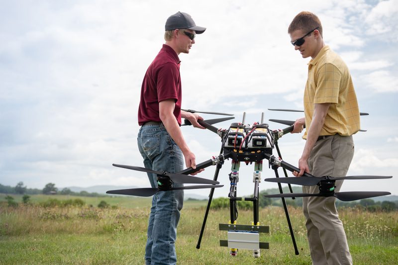 Engineers carry a large drone out into a field to test detect-and-avoid technology. 