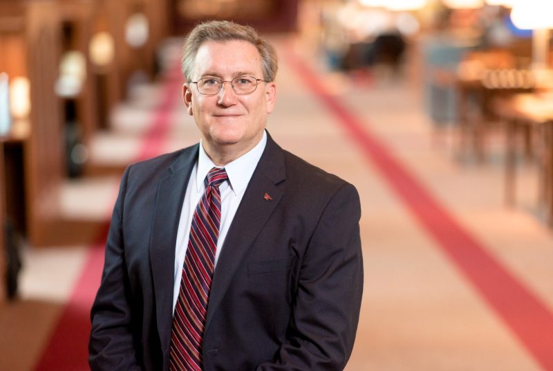 Ron Fricker, wearing a suit sand tie, poses inside Torgersen Bridge.