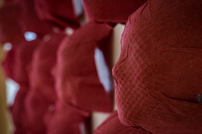 A wall of  more than a dozen red masks despicting human faces