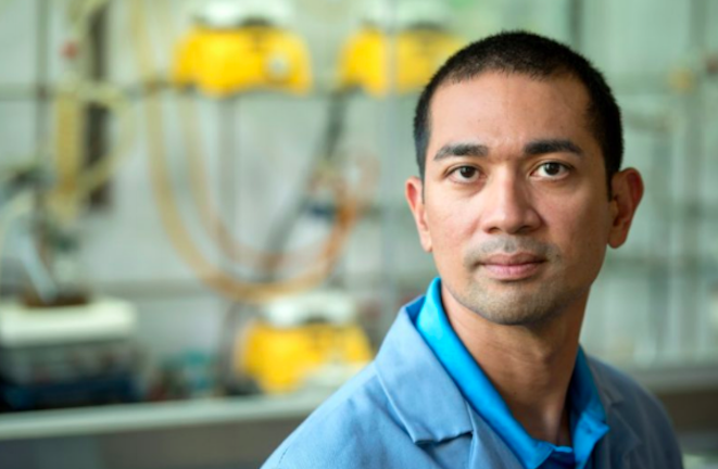 Webster Santos, professor of chemistry and the Cliff and Agnes Lilly Faculty Fellow of Drug Discovery in the College of Science, looks into the camera, with bright yellow instruments blurred out behind him.