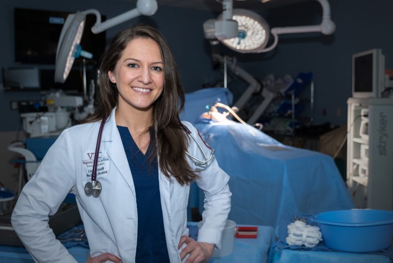 Woman wearing medical white coat standing in dimly lit operating room