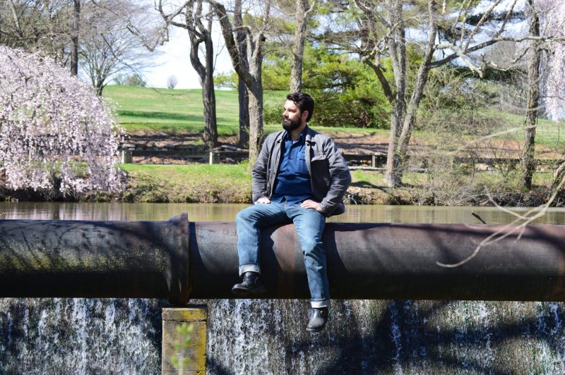 Paolo Scardina, an assistant professor of practice in the Charles E. Via Jr. Department of Civil and Environmental Engineering, sits on a sewer pipe at the spillway of the Virginia Tech Duck Pond. 