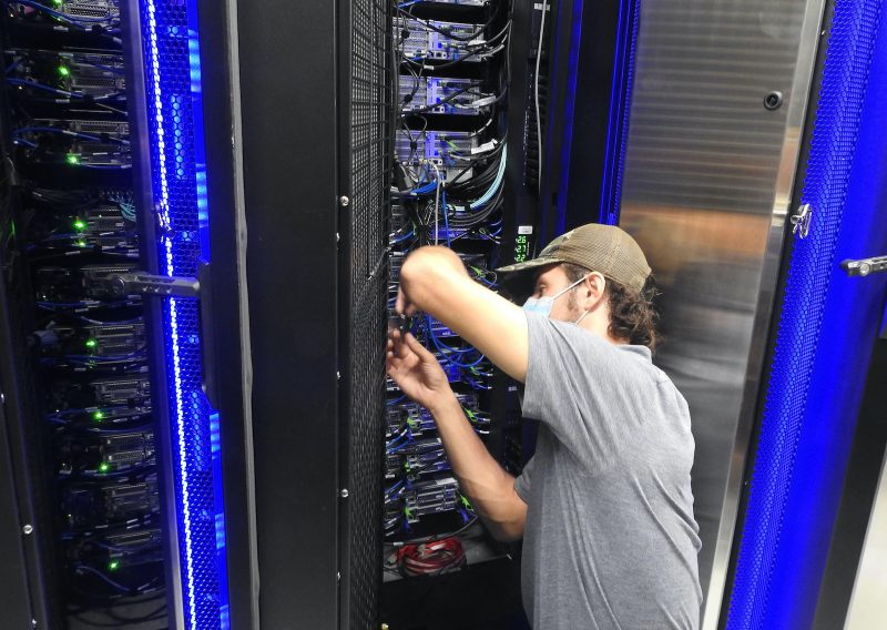 Person adjusting hardware on supercomputer.