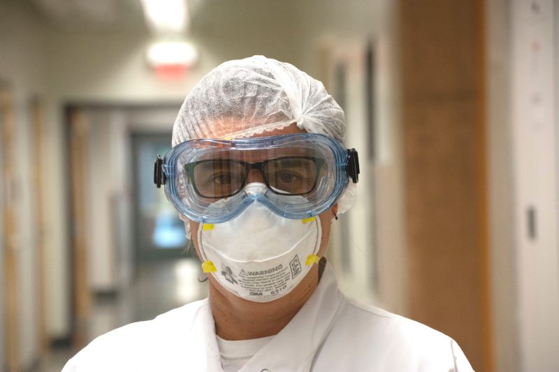 Scientist and Virginia Tech Associate Professor Carla Finkielstein poses for a photograph, wearing a PPE mask, googles, and a hairnet as she works on testing COVID-19 samples.