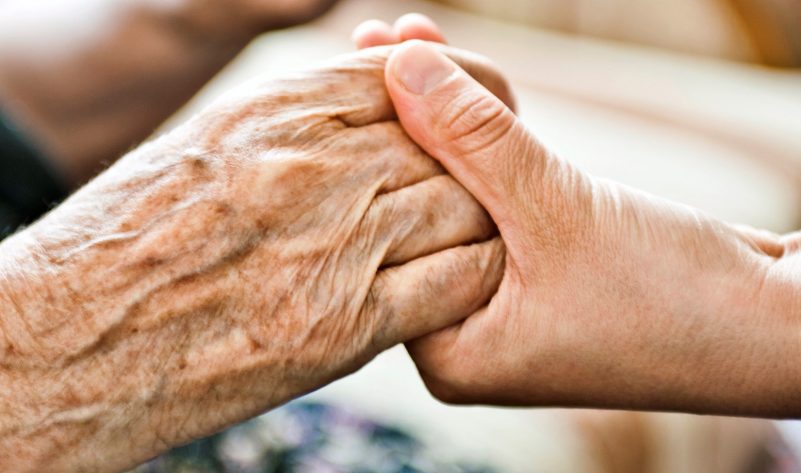 Image of older adults reaching out to hold hands 