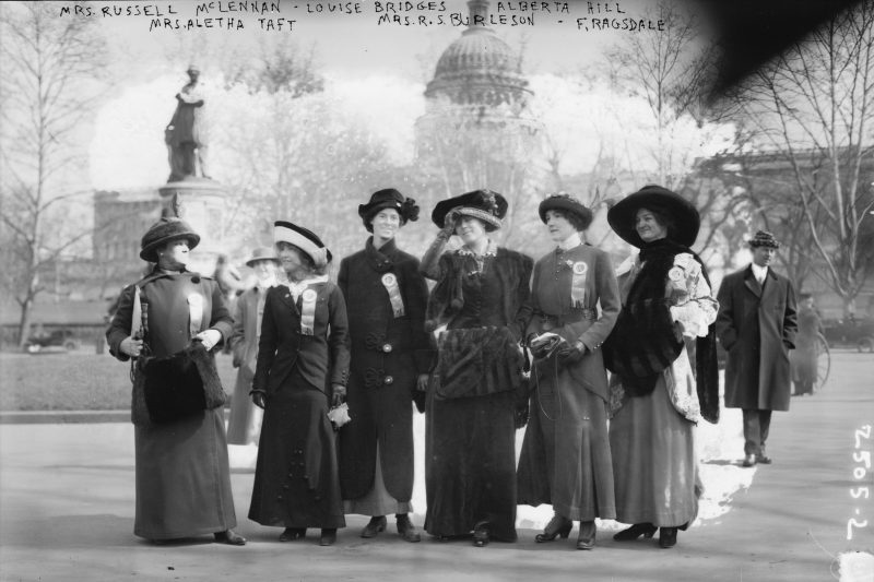 A band of suffragists — including Mrs. Russell McLennan, Aletha Taft, Louise Bridges, Mrs. Richard Coke Burleson, Alberta Hill, and F. Ragsdale — gather in front of the Capitol Building in Washington, D.C. on March 3, 1913. A hand-scrawled notation at the top captures the irony that two of the women were identified by their husband’s names. Photo courtesy of the Library of Congress.