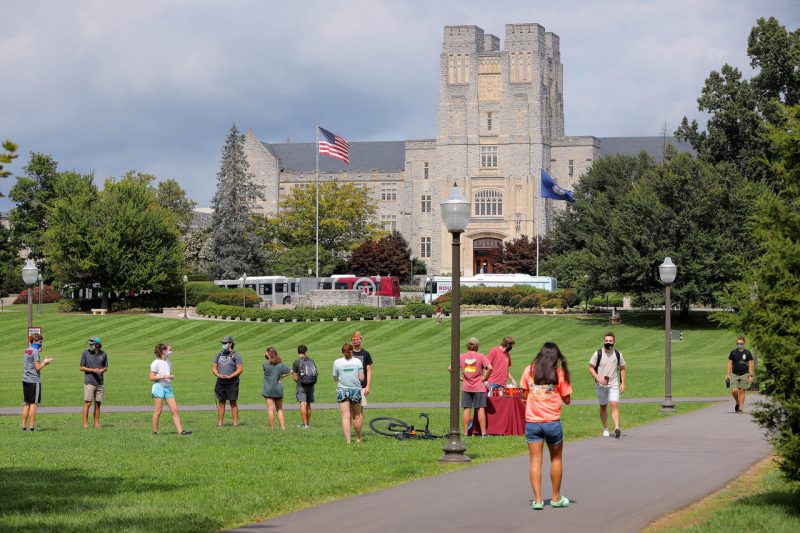 Students wearing masks and standing socially distant on the Drillfield outside Burruss Hall