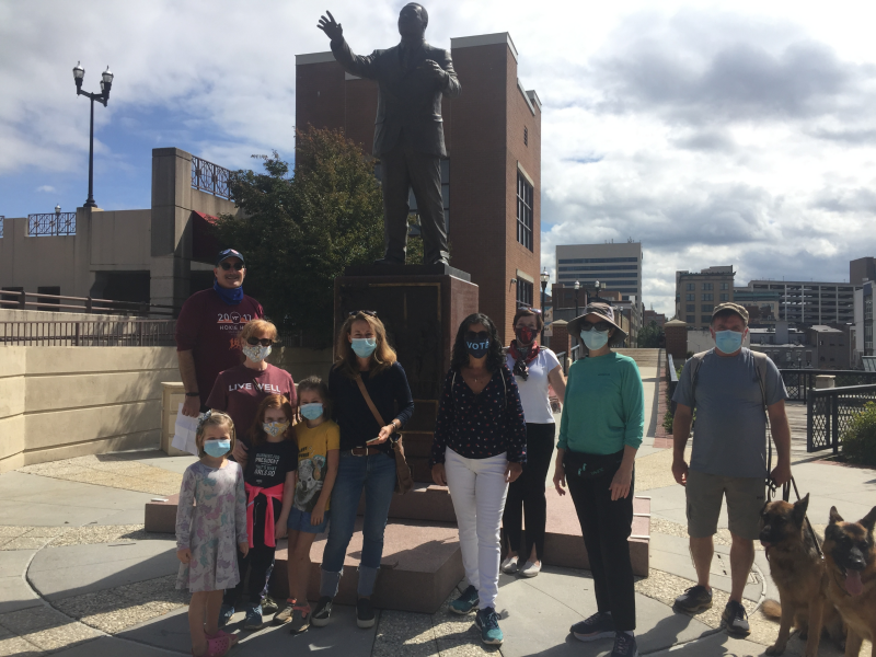 Seven adults, three children, and two dogs stand in front of the Martin Luther King, Jr. statue.
