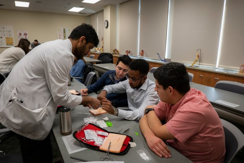 Student shows MEDS Experience participants how to suture