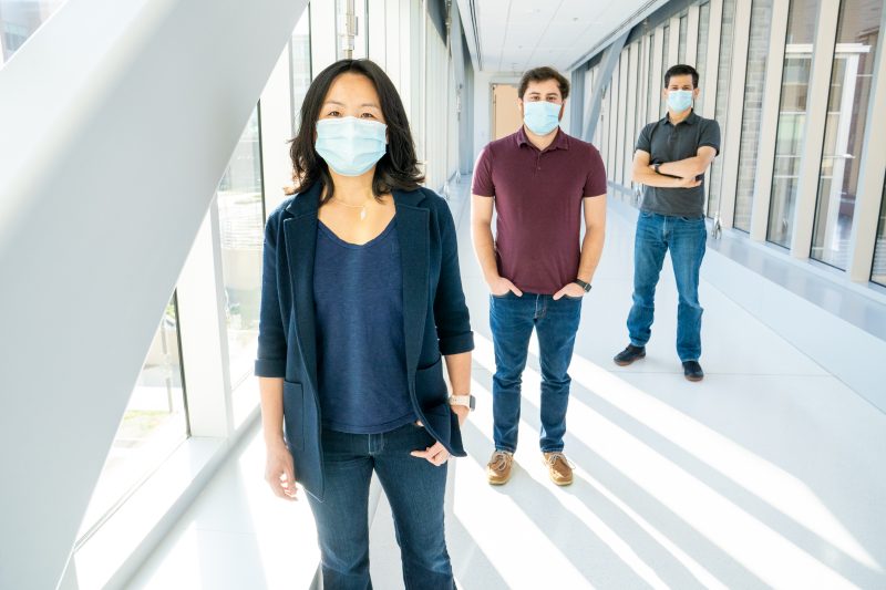 Pearl Chiu, Mark Orloff, and Brooks King-Casas wearing masks and socially distanced standing in hallway