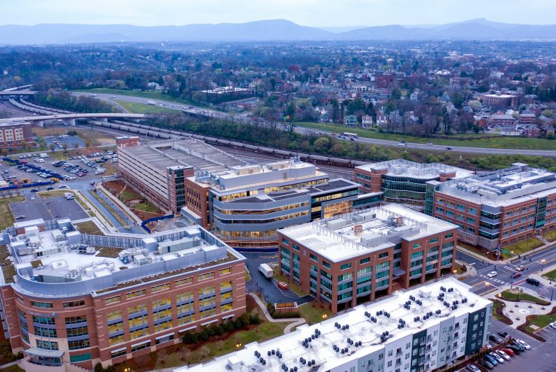 Aerial view of campus with four buildings along with outlying city buildings and mountain range in background.