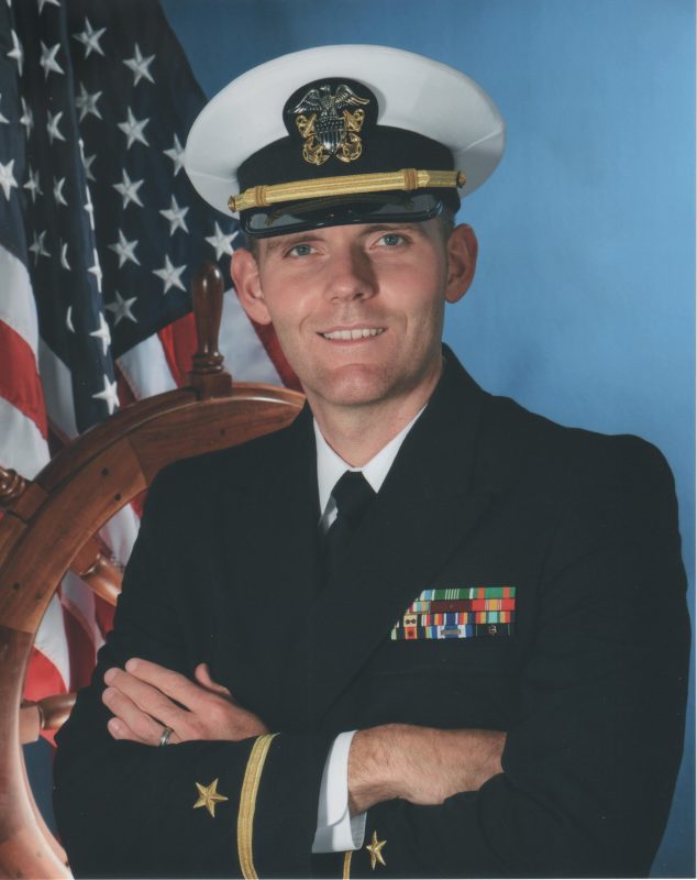 Parks in his Naval Officer commissioning uniform with the American flag in the background.