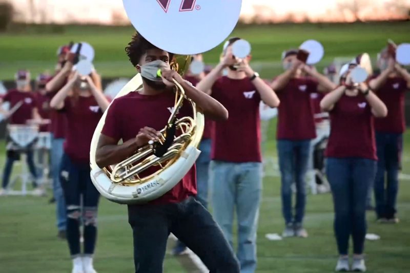 A masked tuba player practices with the Marching Virginians