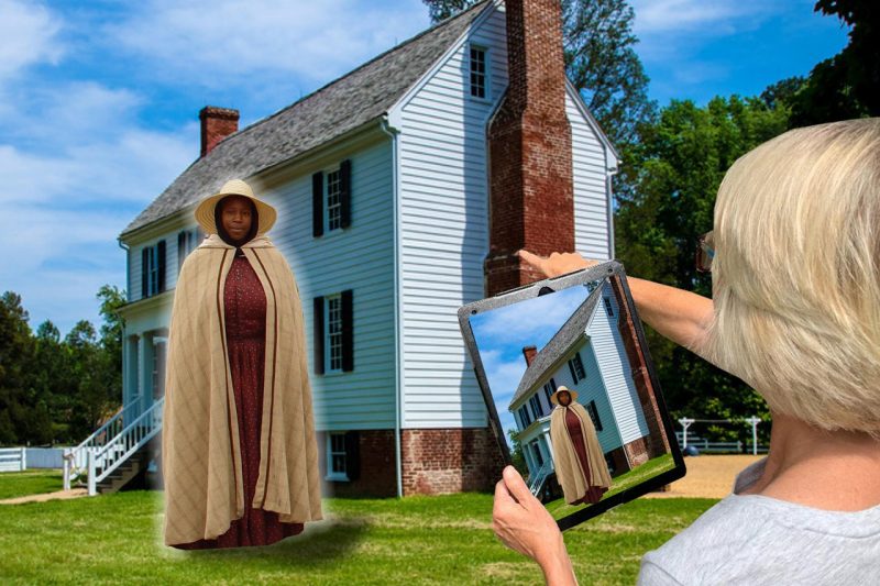 A woman looks at a digital tablet and sees a Civil War era woman standing in front of a historic house