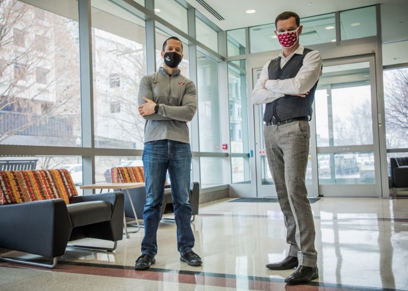 Dirk Buengel, assistant professor of practice in the Pamplin College of Business’ management department, and Eli Vlaisavljevich, assistant professor in biomedical engineering and mechanics, stand in the foyer of Kelly Hall on Virginia Tech campus.