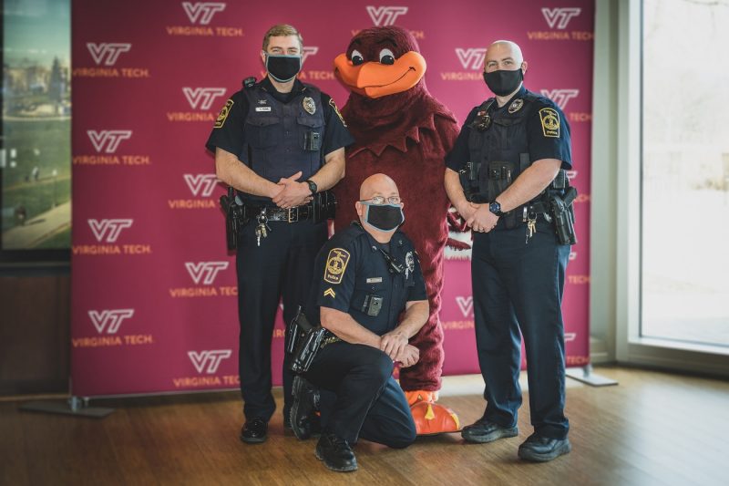 Virginia Tech step-and-repeat background. Virginia Tech Police Department's Residence Life Resource Officers. From left: Officer Micah Pascquarell,  Corporate John Tartar, and Officer Ian McInnis pose with the HokieBird. Sarah Myers for Virginia Tech..