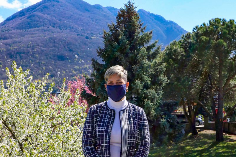 A woman wearing a mask and standing in front of a mountain