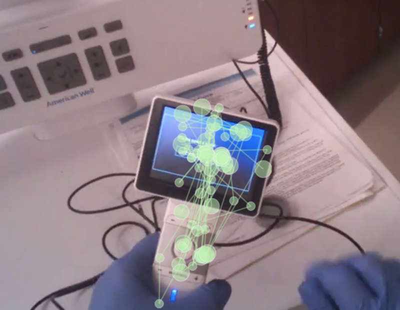 In the background is a handheld peripheral device used as part of the telemedicine cart. In the foreground are a network of green lines and dots showing the path the user's eyes took when using the peripheral device