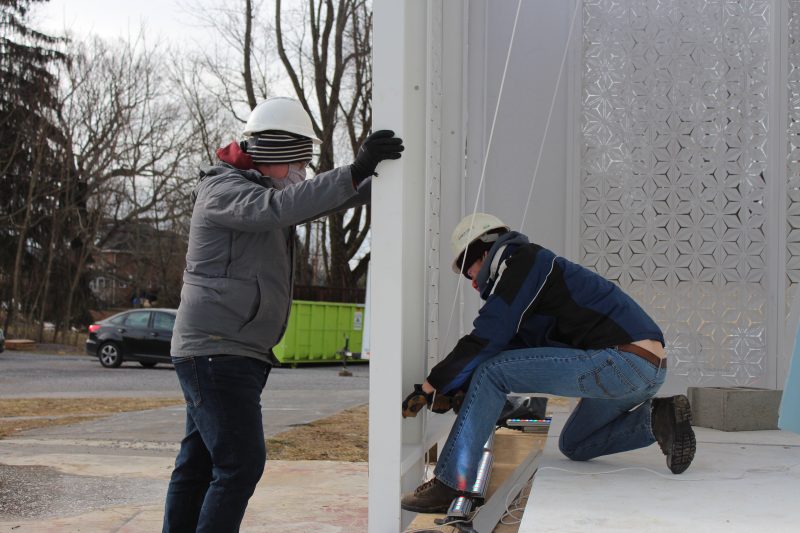 Students work on an exterior wall of FutureHAUS