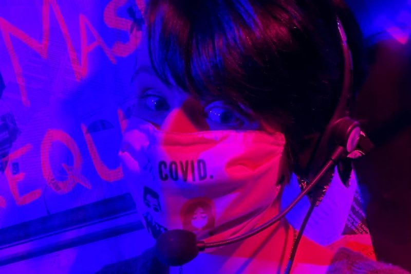 Casey Duke Casey Duke wears a mask. She is lit with purple and fuchsia lights.