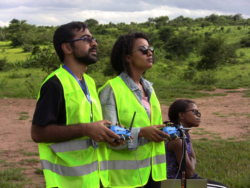 Three students watching a drone fly