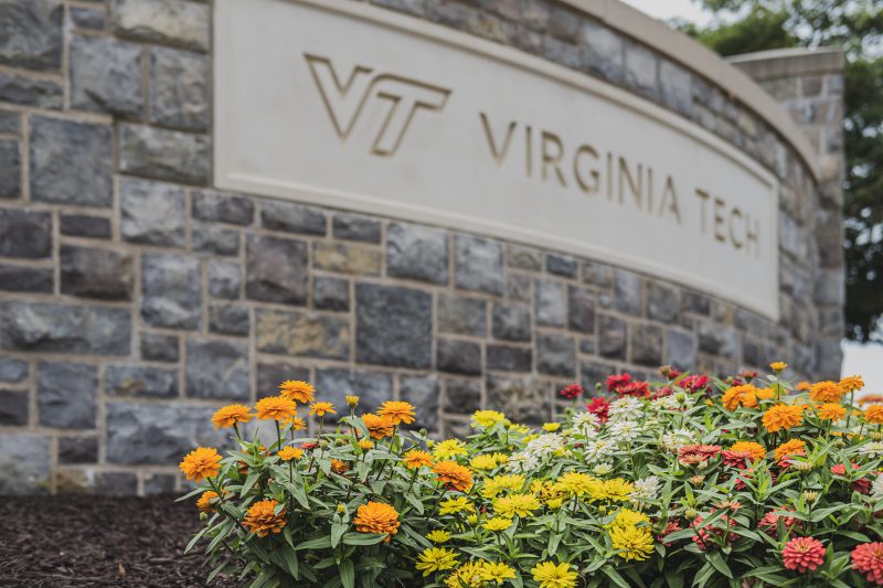 Colorful flowers are planted next to a Hokie Stone sign reading Virginia Tech