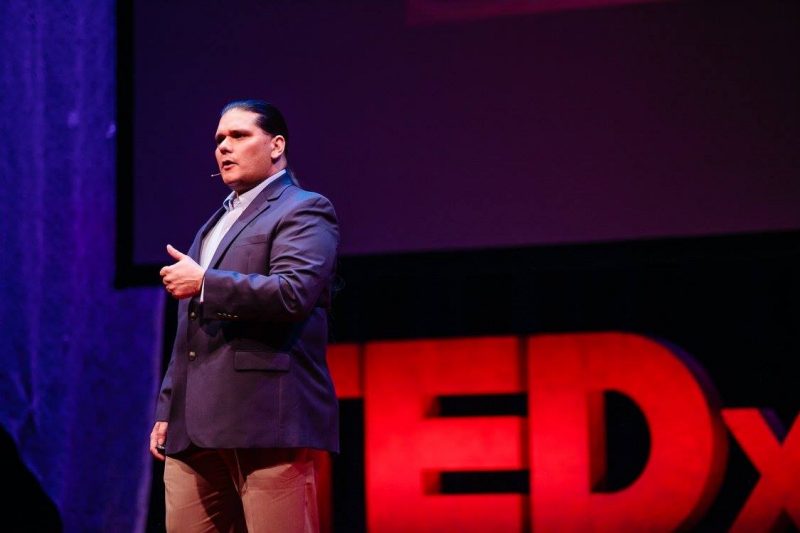 Mike Bowers took the stage at the 2016 TEDxVirginiaTech event in November 2016. In this photo, Bowers is wearing a blazer, dress shirt, and slacks; a TEDxVirginiaTech letter display is behind him.