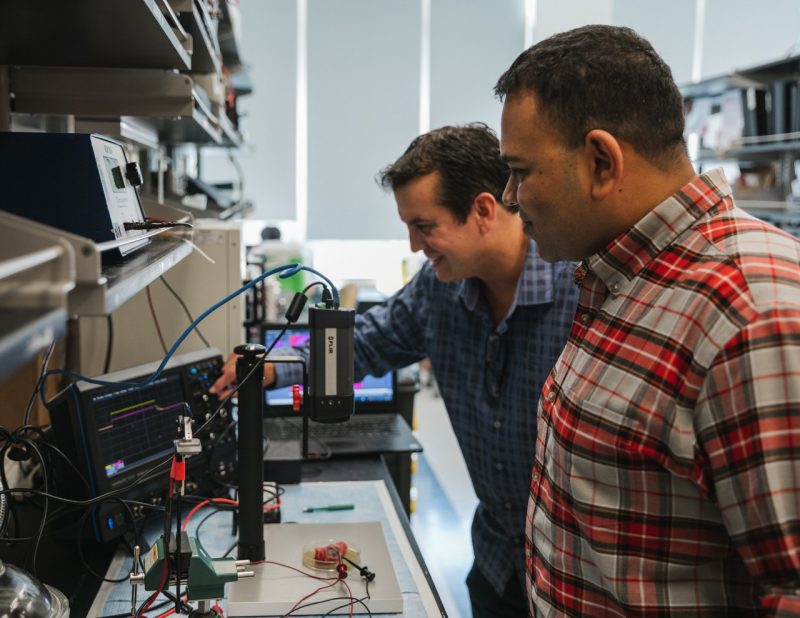 Rafael Davalos and Anand Vadlamani stand in a biomechanical lab, conducting research.