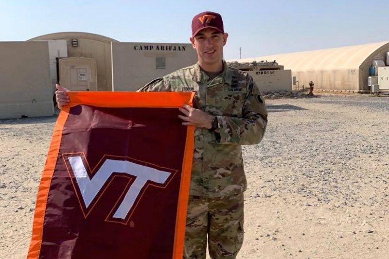 Maj. Justin Laddon holds a Virginia Tech flag in Kuwait.