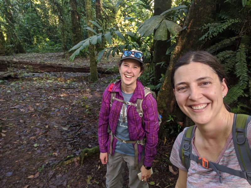 Two people are posing for a selfie in a tropical forest.
