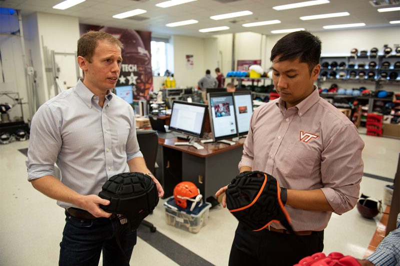 Two researchers in a lab holding soft headgear for flag football. 