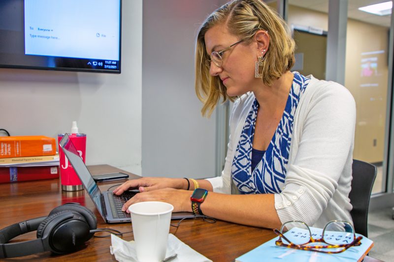 Julie Gerdes, assistant professor of English, sits at a table as she works on her computer to complete a book chapter, which she successfully completed during the research accelerator workshop. 