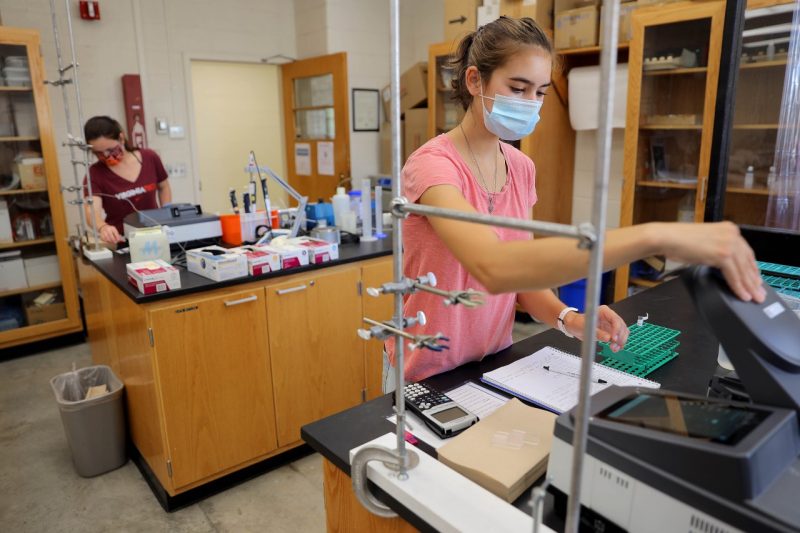 Virginia Tech students, Hannah Lyons (left) and Emma Putnam, work in a campus biochemistry lab while following the university's indoor face mask guidelines. Photo by Ray Meese.