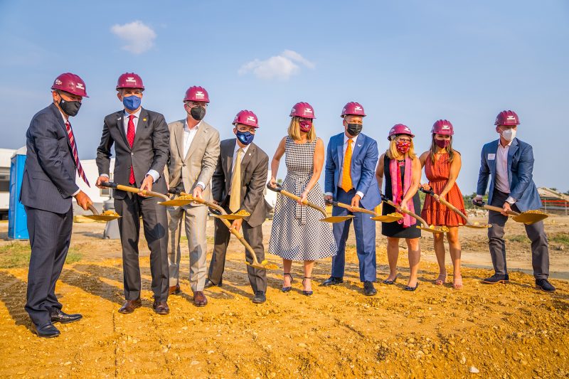 People with shovels and construction helmets at a groundbreaking ceremony