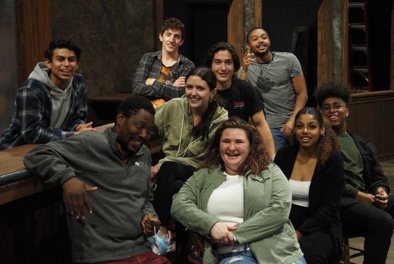 Nine cast members of the show "Sweat" by Lynn Nottage sit at the bar on the set durrng a rehearsal.
