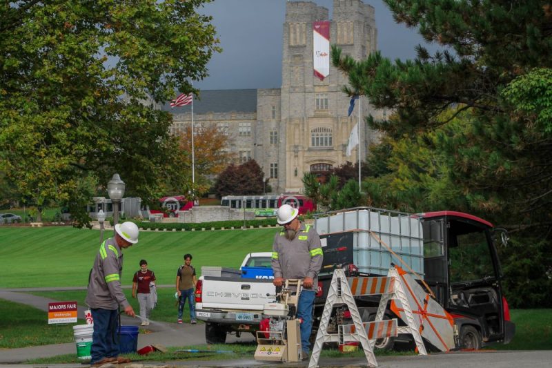 Two members of the pathway enhancement crew in the foreground. Burruss Hall and the Drillfield in the background
