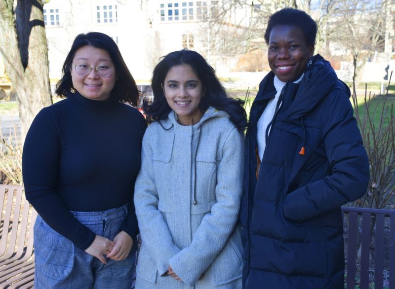 From left to right out front of Derring Hall, students Crystal Lee, Esha Islam, and Asenath Kwagalakwe, all in winter garb and members of the Geodesy and Tectonophysics Laboratory, directed by D. Sarah Stamps.