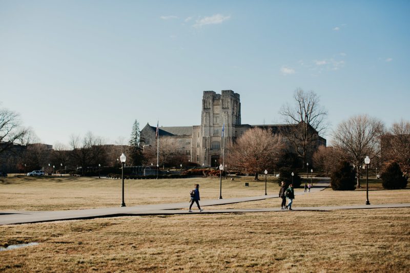 Students walk across the Drillfield in winter. Burruss Hall stands tall in the background.