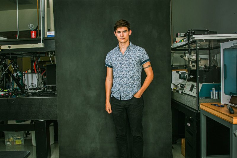 Portrait of Justin Dubik in front of a blue-gray screen in the STRETCH Lab.