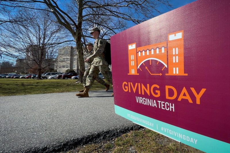 Students in the Virginia Tech Corps of Cadets walk by a Giving Day sign on the Drillfield on Feb. 23. 