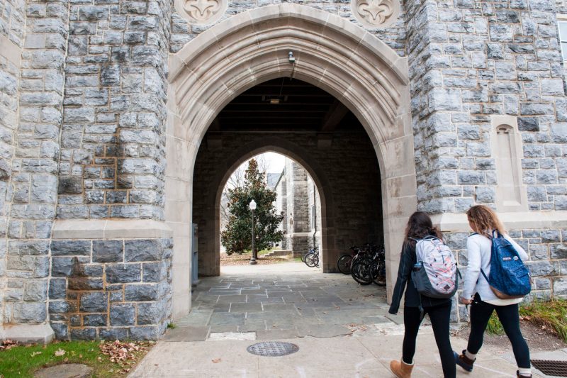 two students wearing backpacks walk into stone archway tunnel on Virginia Tech campus