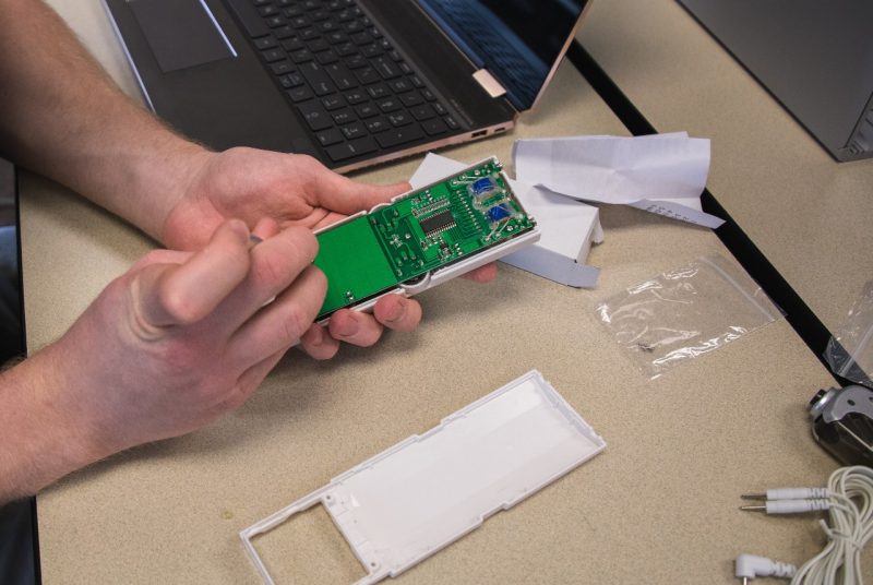 Student takes apart a smaller medical device. Photo shows his hands, holding the open device.