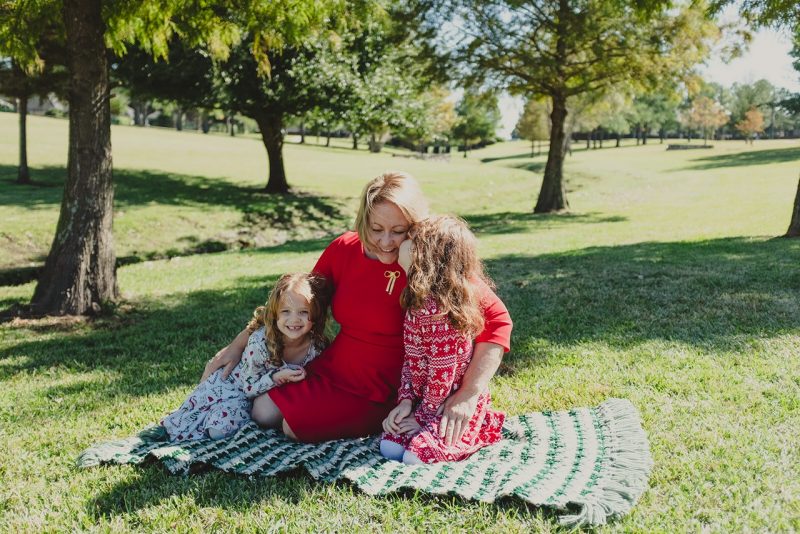 Cherie Poland sitting on lawn with six-year old twin daughters Lela and Kira