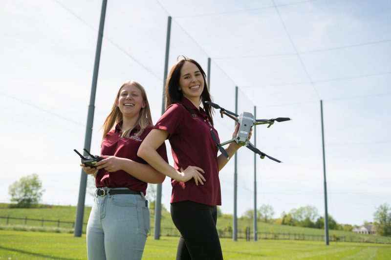 Two women holding a drone and a controller. 