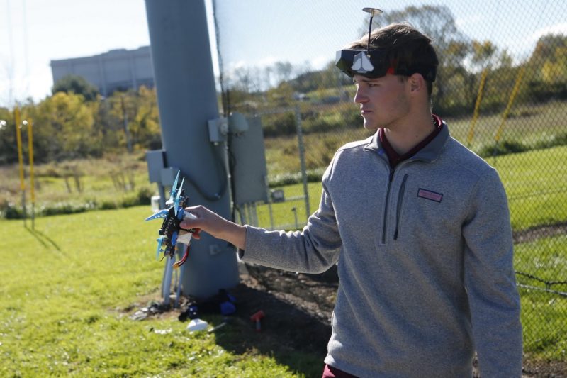 A male student holding a racing drone. 