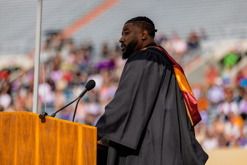 Kevin Jones in commencement regalia standing at podium giving commencement address.
